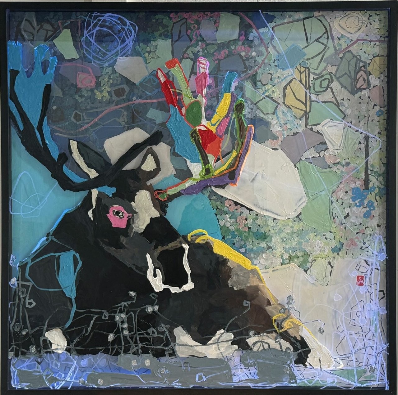 Painting of a reclining dark antlered animal with a pink-ringed eye. Black antlers extend left, while brightly coloured antler shapes rise above its head. Pale overlapping forms, blue-green patches and looping lines fill the surrounding woodland scene.